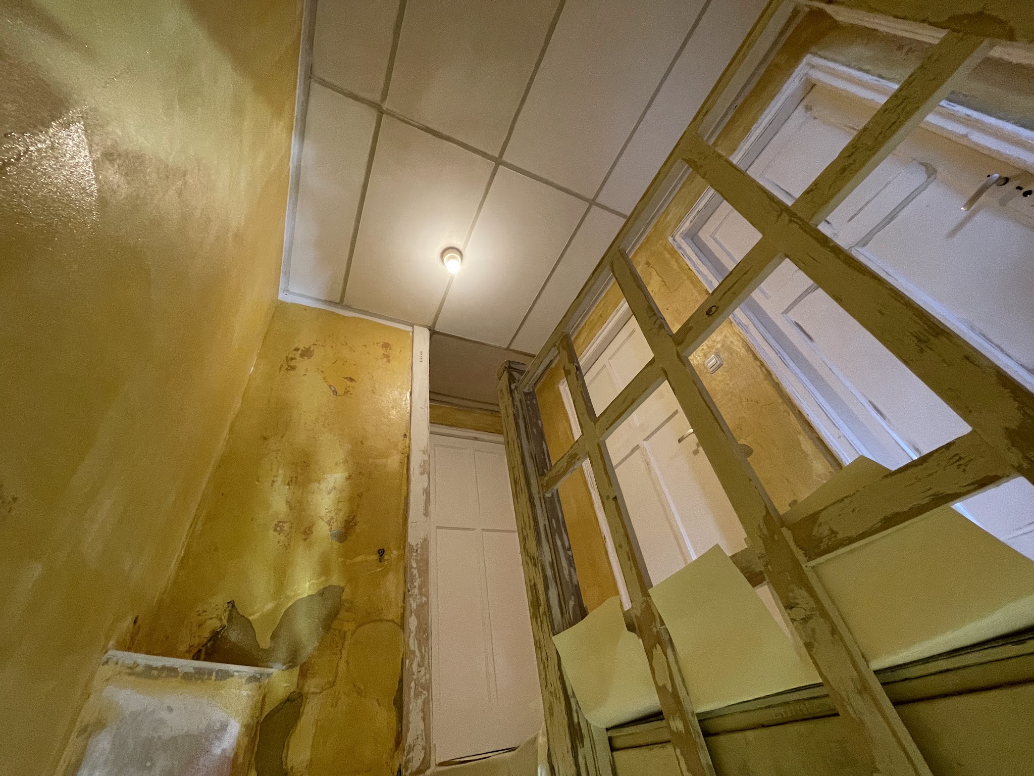 Plafond en wand in voorbereiding naast een raam met houten regelwerk