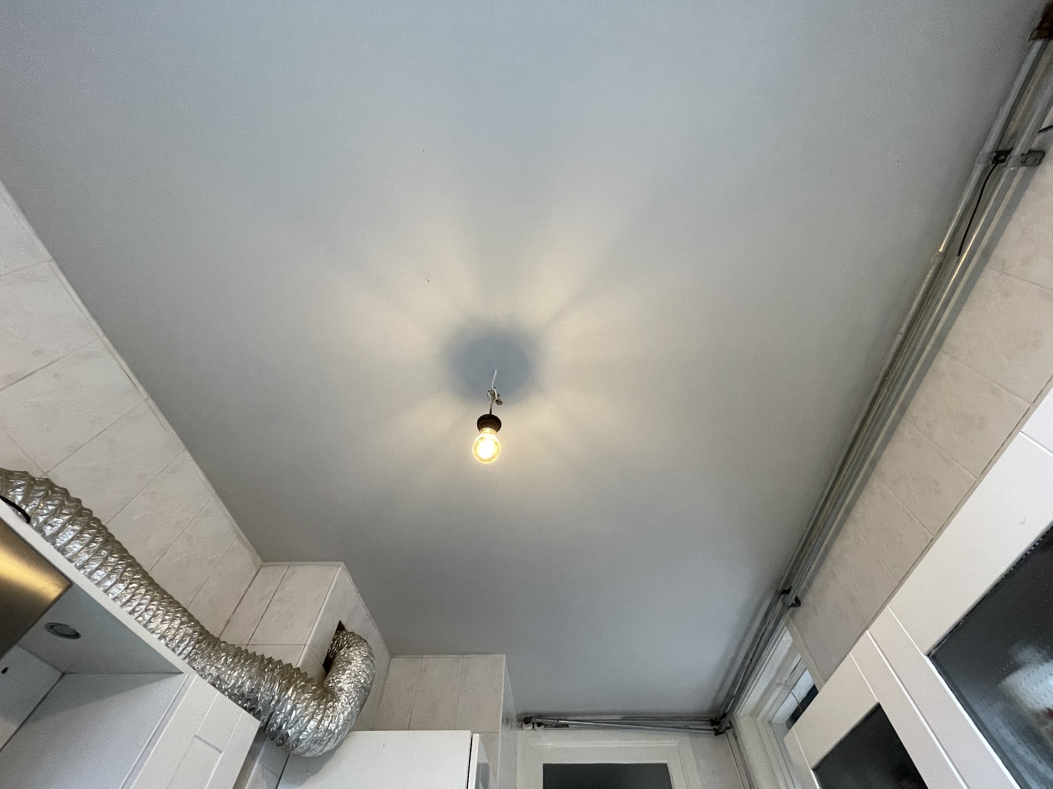 Strak wit gestuct plafond met lamp tijdens een verbouwing
